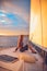 Girl with long hair sitting at the stern of the yacht and looks into the distance at sunset