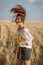 Girl with long hair on straw field with wildflower bouquet