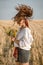 Girl with long hair on straw field with wildflower bouquet