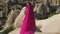 Girl in a long purple dress stands high on a rock in Cappadocia