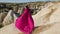 Girl in a long purple dress stands high on a rock in Cappadocia