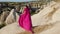 Girl in a long purple dress stands high on a rock in Cappadocia