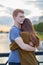 Girl with long thick dark hear embracing redhead boy in the blue t-shirt on bridge, teen love at sunset