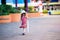 Girl looked down at the ground. Child holds white umbrella that is folded away.