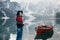 Girl looking behind. Outstanding view. Woman in black hat enjoying majestic mountain landscape near the lake with boat