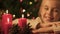 Girl looking at burning candles, happy childhood and faith in Christmas miracle