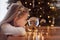 Girl looking at a glass ball with a scene of the birth of Jesus Christ in a glass ball on a Christmas tree