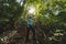 Girl looking up at the trees inside the jungle, hiking through a green forest jungle, Thailand