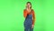 Girl looks around, covers her mouth with her hand and whispers the secret and making a hush gesture. Green screen