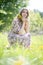 Girl looks away sitting on the lawn of the Park with flowers in her hand on a clear warm day