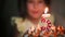 The girl looks at the burning candle with the number 5 on the cake and makes a wish. Birthday, fifth anniversary, five years, cand