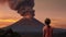 Girl looks at erupting volcano at sunset eruption disaster