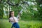 Girl looks through her fingers under the apple tree