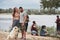 Girl looks at her man with love. Group of people have picnic on the beach. Friends have fun at weekend time