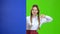 Girl looks out from behind a blue board and shows a thumbs down . Green Screen