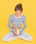 Girl in lotus pose holding healthy organic snack