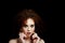 A girl with lush curly red hair. Close face with bright make-up and massive earrings.Purple shadows. Bare shoulders. The