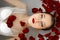 The girl is lying in the bathroom with rose petals. A wellness bath with roses.