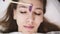 Girl lying on couch during eyebrowes treatment at studio beauty, beautician depilating and shaping brows at beauty salon