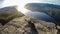 A girl lying on the edge of the famous Preikestolen rock in Norway. A sunset is taking place over a fjord.