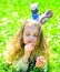 Girl lying on grass, grassplot on background. Girl on dreamy face holds daisy flower. Child enjoy spring sunny weather