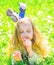 Girl lying on grass, grassplot on background. Girl on dreamy face holds daisy flower. Child enjoy spring sunny weather