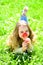 Girl lying on grass, grassplot on background. Girl on smiling face holds red tulip flower, enjoy aroma. Child enjoy