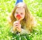 Girl lying on grass, grassplot on background. Girl on smiling face holds red tulip flower, enjoy aroma. Tulip fragrance