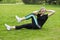 Girl lying on the grass in the park performs exercises to strengthen the muscles of the abs