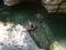 A girl lying on an inflatable swimming ring floats in a calm backwater of a canyon gorge. Top view