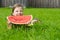 Girl lying on the lawn. and holding a large slice of watermelon on a green background