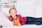 Girl lying on sofa holding piggy bank