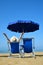 Girl lying on a sun lounger under an umbrella on sandy beach.