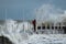 Girl makes extreme selfie on the pier against the background of waves with a risk to life