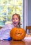 girl makes a goofy smile as she poses with her jack o lantern