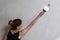 The girl makes the repair of the apartment. A woman leads a spatula on a concrete wall.