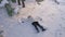 The girl makes a snow angel in a clearing in the forest, a shot from above. Happy young woman moves her arms and legs