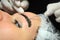 Girl with makeup lying on procedure of microblading. Cosmetologist makes permanent makeup on the eyebrows