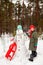 Girl making  snowman  in winter  forest