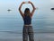 Girl making two peace signs wearing flowy leggings and a blue crop top looking over a lake