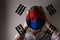 Girl in a mask against the background of the South Korea flag; danger of disease, new virus