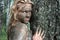 Girl with a mask of mud near a tree trunk in an ecological resort. Beautiful blonde