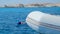 A girl in a mask snorkels in the sea, an inflatable boat is moored nearby,