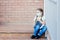 A girl in a mask with two pigtails sits on the street porch of the entrance and looks away