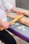 Girl massage therapist does anti-cellulite massage to a girl on a massage table in a spa salon with a bamboo stick. Spa treatments