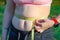 The girl measures her waist, a whirlpool with a yellow centimeter. Fat belly, folds of fat. Sports, proper nutrition, weight  loss