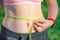 The girl measures her waist, a whirlpool with a yellow centimeter. Fat belly, folds of fat. Sports, proper nutrition, weight  loss