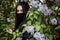 Girl in a medical mask on a background of blooming lilacs. Black mask.