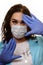 A girl in a medical mask, gloves and a robe on a white background. Beautician, beauty specialist. White-blue tones photo