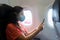 A girl in a medical mask on her face during a flight in the cabin. Air travel during a pandemic